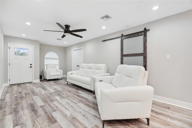 sitting room featuring recessed lighting, a barn door, baseboards, and light wood finished floors