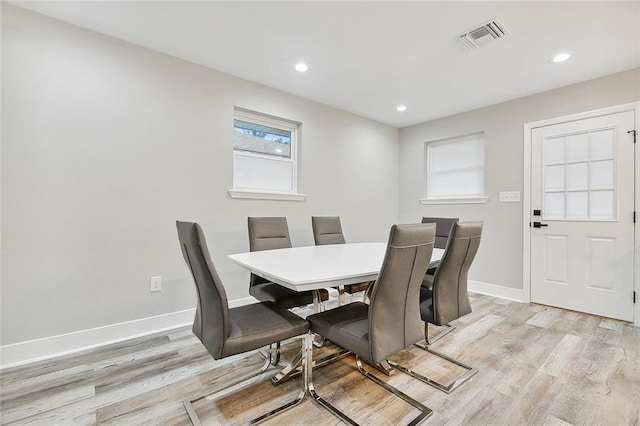 dining area with light wood finished floors, visible vents, and baseboards