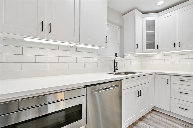 kitchen featuring a sink, white cabinetry, stainless steel appliances, light countertops, and decorative backsplash