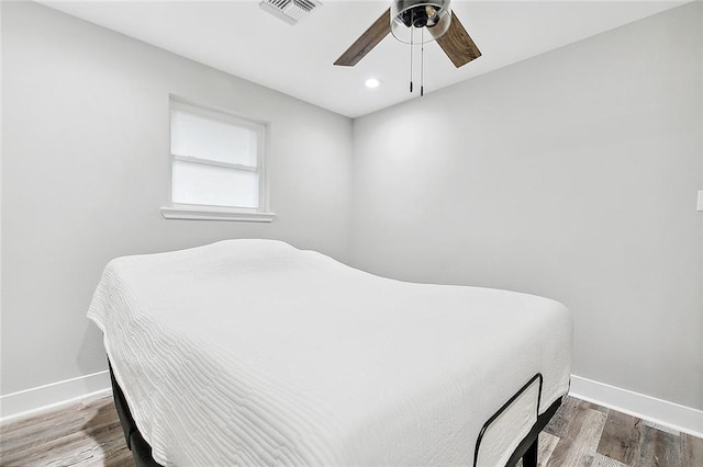 bedroom with ceiling fan, wood finished floors, visible vents, and baseboards