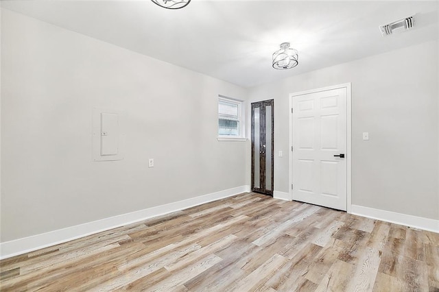 spare room featuring light wood-style floors, visible vents, and baseboards