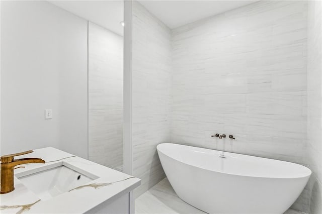 bathroom with vanity, a tub to relax in, and tile walls