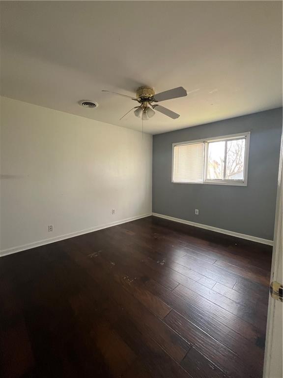 unfurnished room featuring dark wood-type flooring and ceiling fan