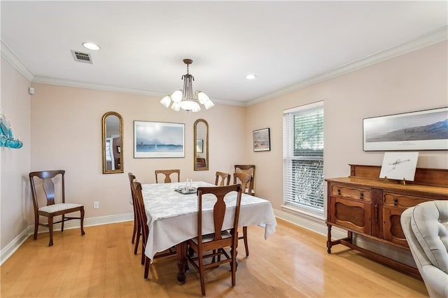 dining area featuring an inviting chandelier, ornamental molding, and light wood-type flooring