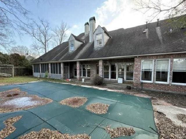 rear view of property featuring a covered pool