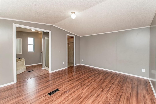 unfurnished bedroom with hardwood / wood-style flooring, ornamental molding, lofted ceiling, and a textured ceiling