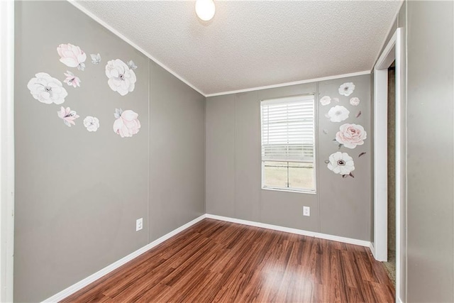 spare room featuring dark wood-type flooring, ornamental molding, and a textured ceiling