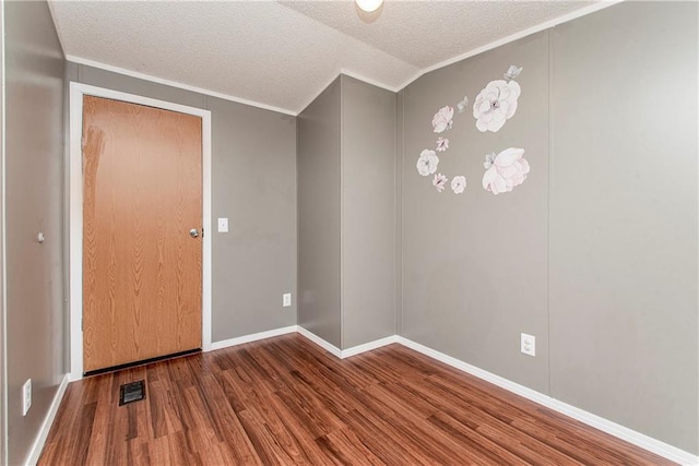 empty room featuring vaulted ceiling, crown molding, hardwood / wood-style floors, and a textured ceiling