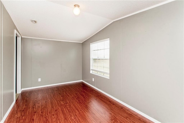 empty room featuring crown molding, vaulted ceiling, hardwood / wood-style floors, and a textured ceiling