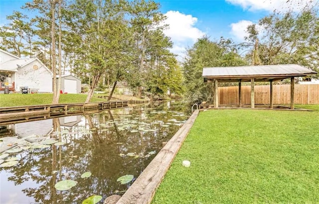 view of dock with a water view, a gazebo, and a lawn