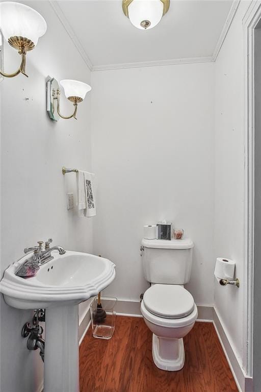 bathroom with hardwood / wood-style flooring, crown molding, and toilet