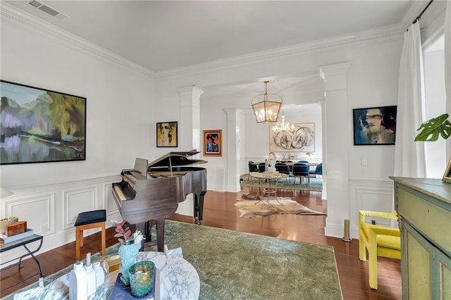 2809 Prytania St, New Orleans, LA 70115 - sitting room featuring decorative columns, a chandelier, crown molding, dark wood-style floors, and a decorative wall