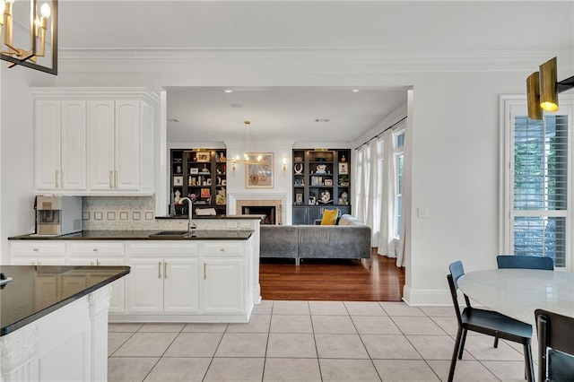 2809 Prytania St, New Orleans, LA 70115 - kitchen featuring a sink, light tile patterned flooring, white cabinets, a chandelier, and hanging light fixtures