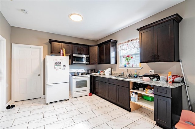 kitchen featuring dark brown cabinetry, sink, white appliances, and light stone countertops