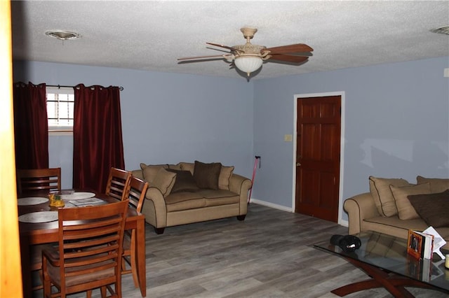 living room with hardwood / wood-style flooring, ceiling fan, and a textured ceiling