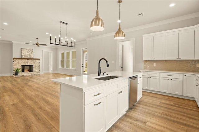 kitchen with an island with sink, white cabinetry, light countertops, and stainless steel dishwasher