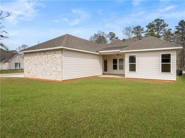 rear view of house with a patio area, a lawn, and roof with shingles