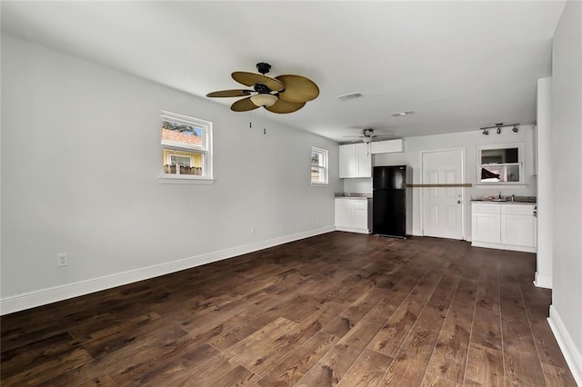 unfurnished living room featuring dark wood-type flooring, ceiling fan, and sink