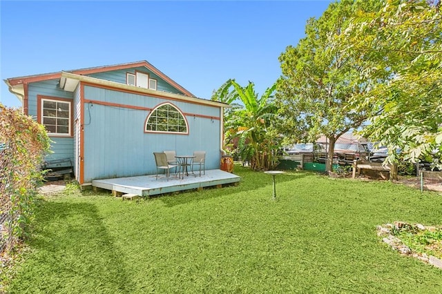 back of house with a wooden deck and a lawn