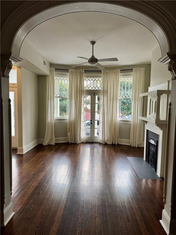 unfurnished living room with hardwood / wood-style flooring, a healthy amount of sunlight, and arched walkways