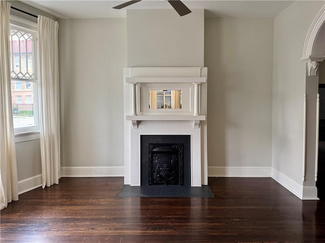 unfurnished living room featuring a fireplace with flush hearth, wood finished floors, baseboards, and ceiling fan