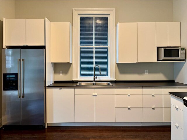 kitchen featuring white microwave, a sink, white cabinets, dark countertops, and high quality fridge