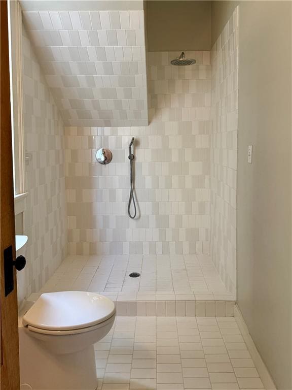 full bath featuring toilet, tile patterned flooring, and a tile shower