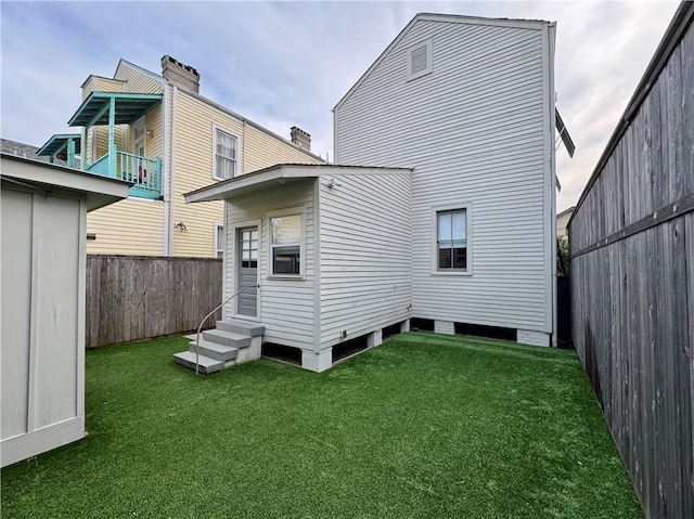 back of property with a yard, a fenced backyard, and entry steps