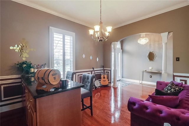 office space featuring an inviting chandelier, crown molding, wood-type flooring, and decorative columns
