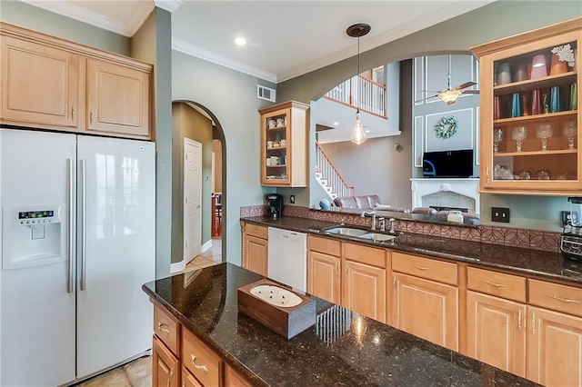 kitchen with sink, crown molding, decorative light fixtures, white appliances, and dark stone counters