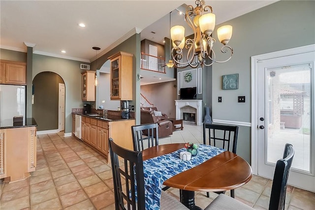 dining space featuring ornamental molding, sink, and a notable chandelier