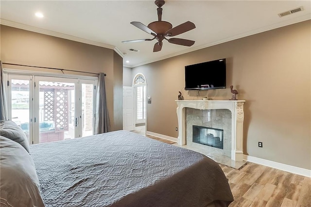 bedroom featuring a fireplace, ornamental molding, access to exterior, ceiling fan, and light hardwood / wood-style floors