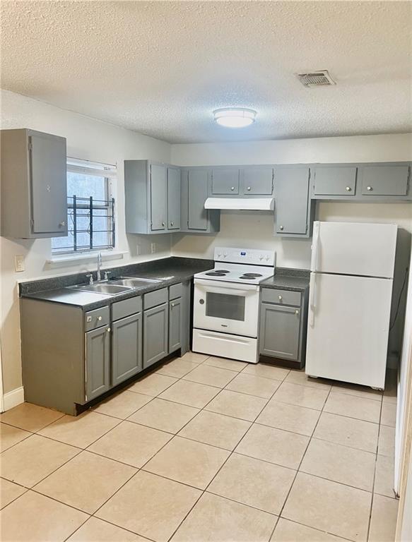 kitchen featuring white appliances, light tile patterned floors, sink, and gray cabinetry