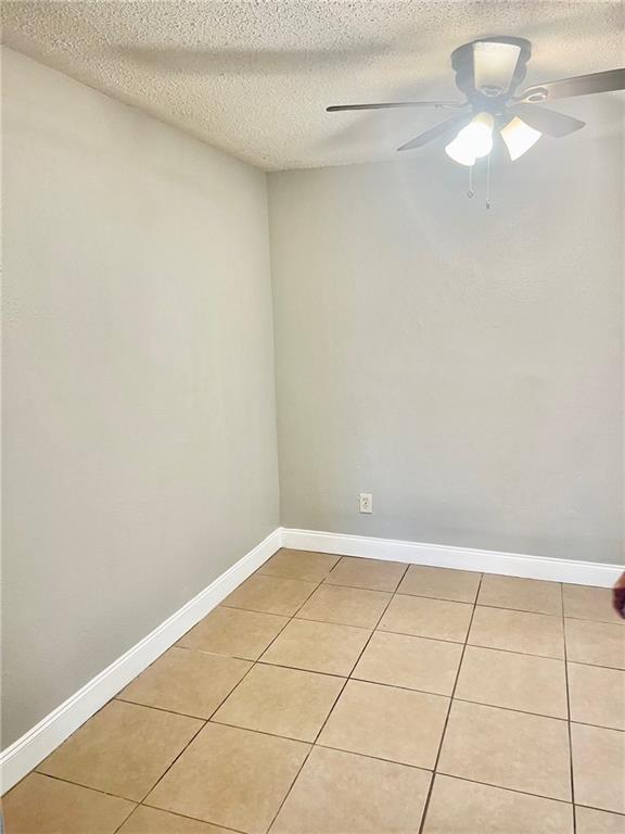 spare room with ceiling fan, a textured ceiling, and light tile patterned floors