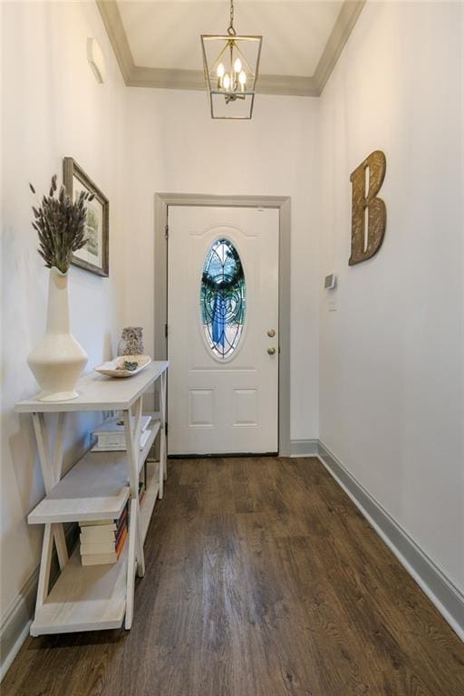 entrance foyer featuring dark hardwood / wood-style flooring, ornamental molding, and an inviting chandelier