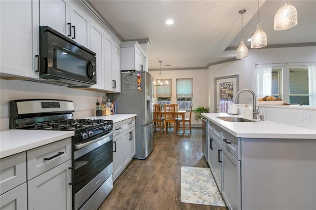 kitchen featuring sink, appliances with stainless steel finishes, hanging light fixtures, dark hardwood / wood-style floors, and an island with sink