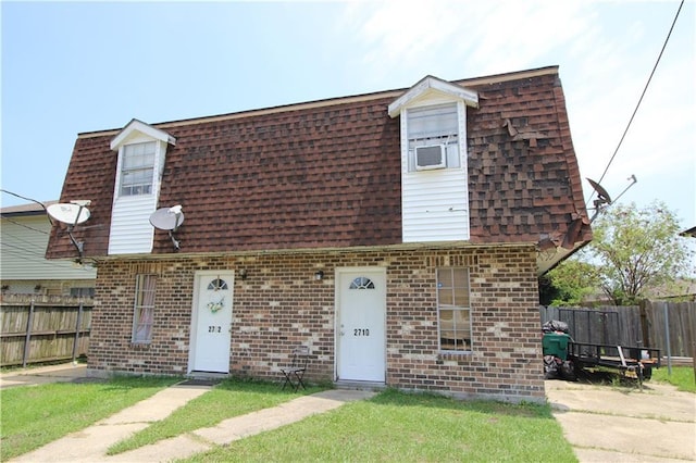 view of front of house with brick siding, fence, a shingled roof, and mansard roof