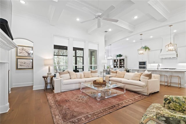 living room with ceiling fan with notable chandelier, beamed ceiling, ornamental molding, coffered ceiling, and light wood-type flooring