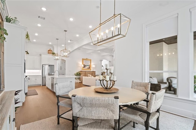 dining space with crown molding and light wood-type flooring