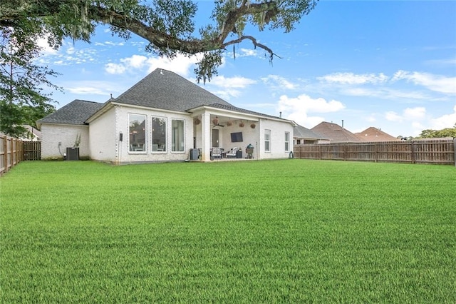 rear view of property featuring a lawn and ceiling fan