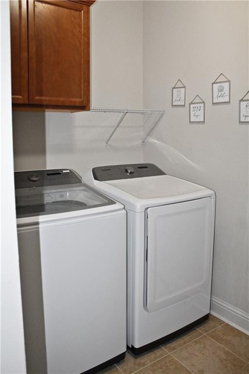 laundry room with tile patterned floors, washing machine and dryer, and cabinets