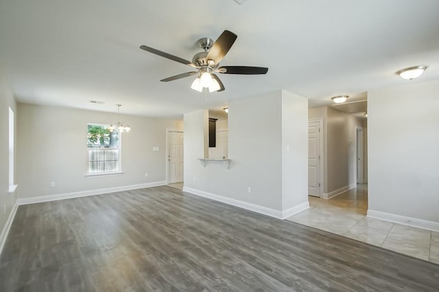 unfurnished room featuring ceiling fan with notable chandelier and dark hardwood / wood-style floors