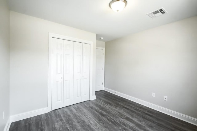 unfurnished bedroom featuring a closet and dark hardwood / wood-style floors