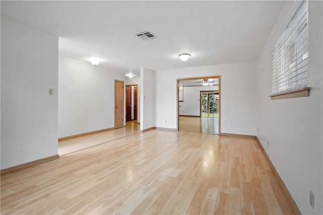 unfurnished room with ceiling fan, visible vents, light wood-style floors, and baseboards