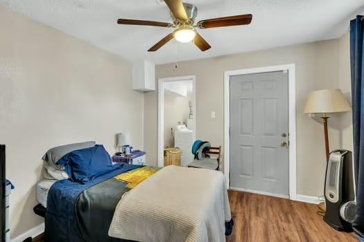 bedroom with connected bathroom, hardwood / wood-style flooring, and ceiling fan