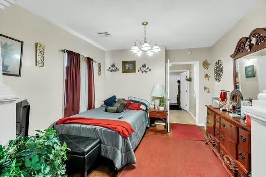 carpeted bedroom with a notable chandelier