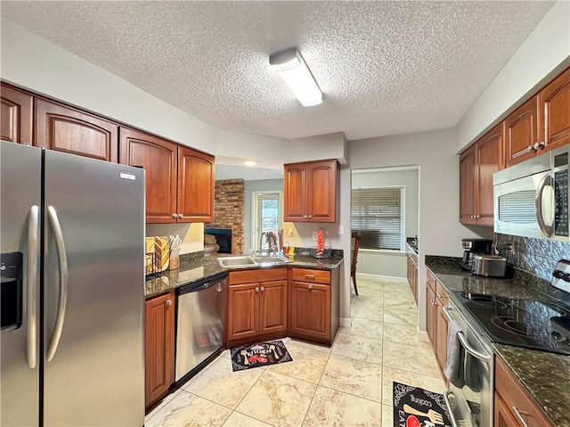 kitchen with stainless steel appliances, sink, a textured ceiling, and dark stone countertops