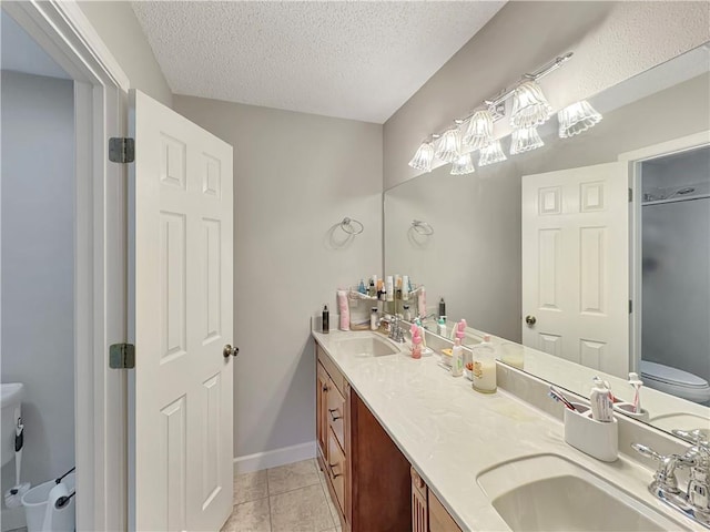 bathroom featuring tile patterned floors, toilet, a textured ceiling, and vanity