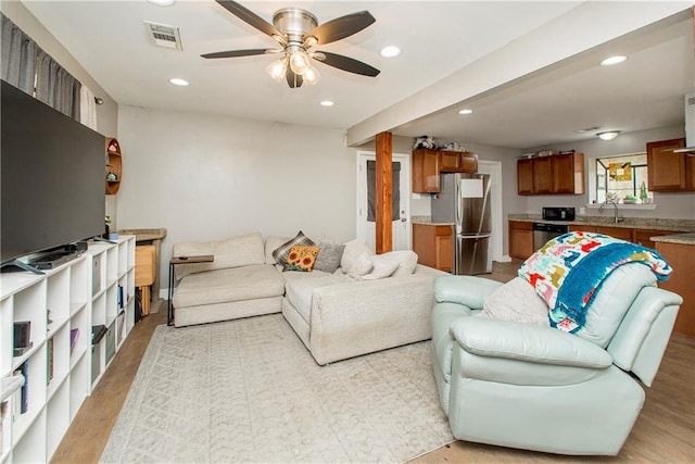 living room with sink, ceiling fan, and light hardwood / wood-style flooring