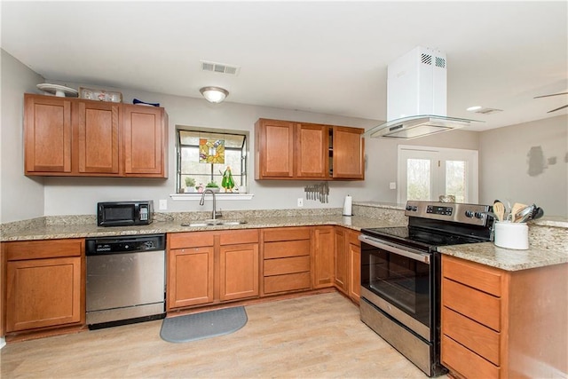 kitchen featuring appliances with stainless steel finishes, island range hood, sink, light stone counters, and light hardwood / wood-style floors